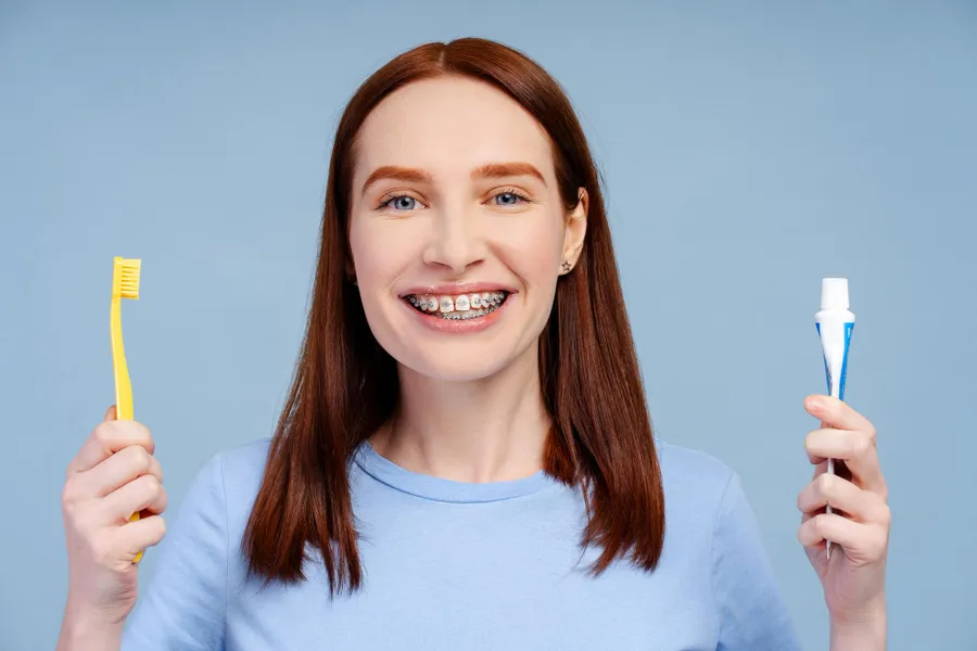 Primo piano di una persona che lava i denti con l'apparecchio usando uno spazzolino ortodontico