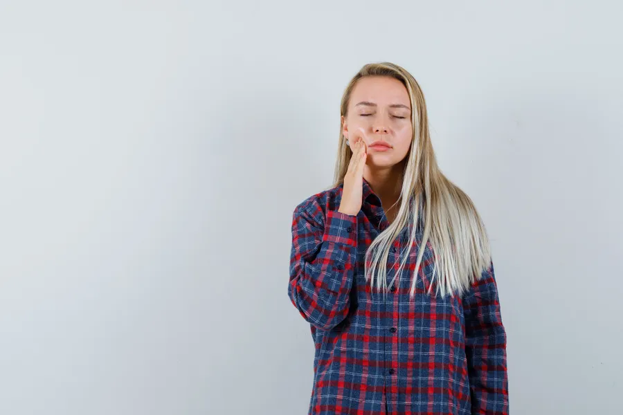 Woman touching her cheek in discomfort from a sensitive tooth