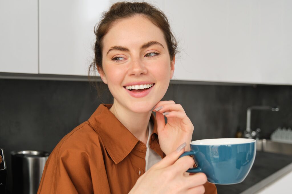 close up portrait happy beautiful woman drinking cup tea kitchen holding mug with fresh Does Coffee Stain Your Teeth More Than Tea?